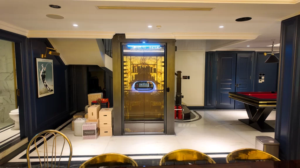 Lift rumah Kalea di ruang keluarga dengan pintu kaca dan interior premium