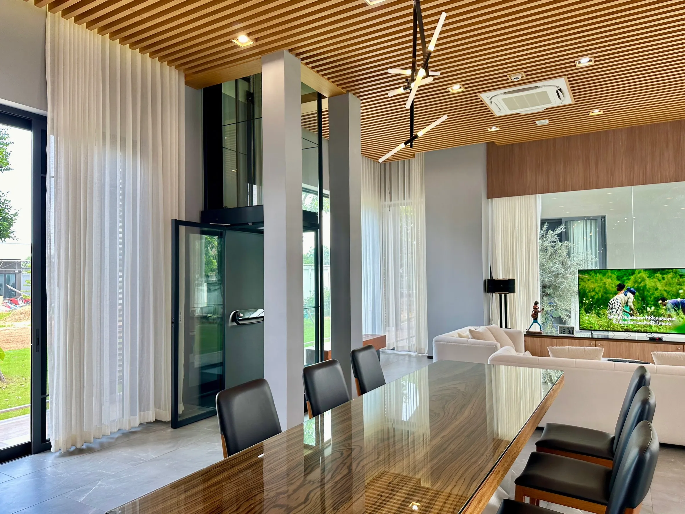 Kalea Home Lift Products 1 Lift rumah Kalea di ruang keluarga modern dengan shaft kaca dekat area makan